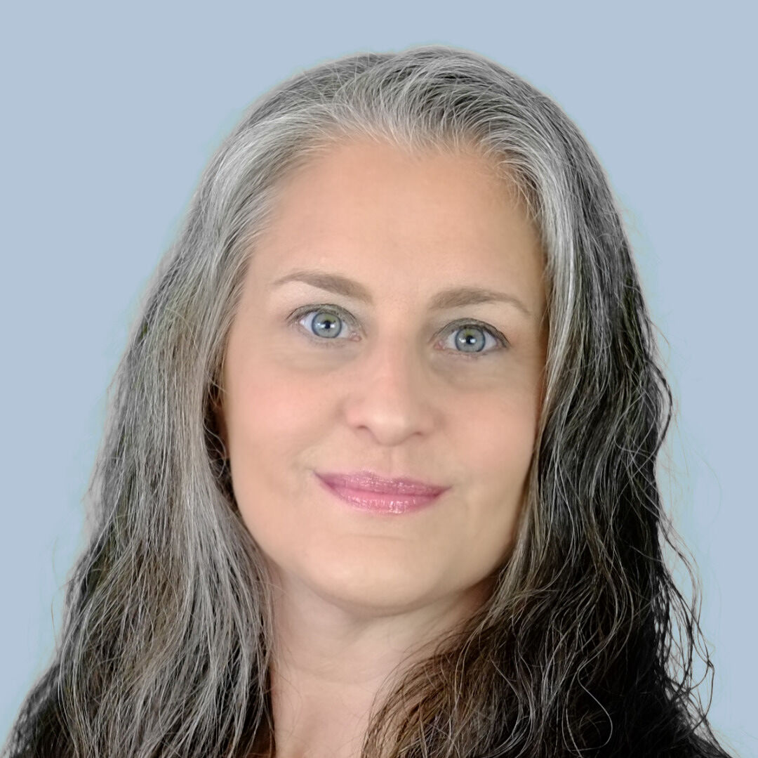 Portrait of Debbie Levitt, a middle aged woman with long hair, smiling at the camera